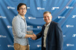 Two people smiling and shaking hands, one holding an award, against a backdrop with "Penn" and "Venture Lab" logos.