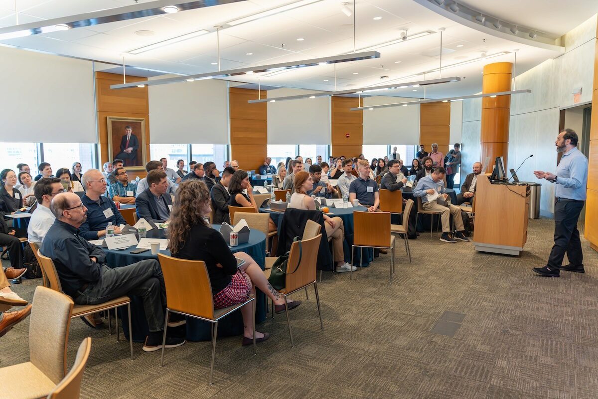AIFOW-4 A person is giving a presentation to a large group of people seated at tables in a modern conference room, indicating a seminar or professional event.