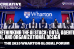 Panel discussion at the 2025 Wharton Global Forum with several participants seated on a stage. The backdrop displays "Wharton University of Pennsylvania" and text about rethinking AI stack, data, and organizational design.