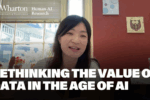 A person speaking in an office environment with a window and wall art in the background, overlaid with text: "Rethinking the Value of Data in the Age of AI." The Wharton School and Human-AI Research logos are visible.